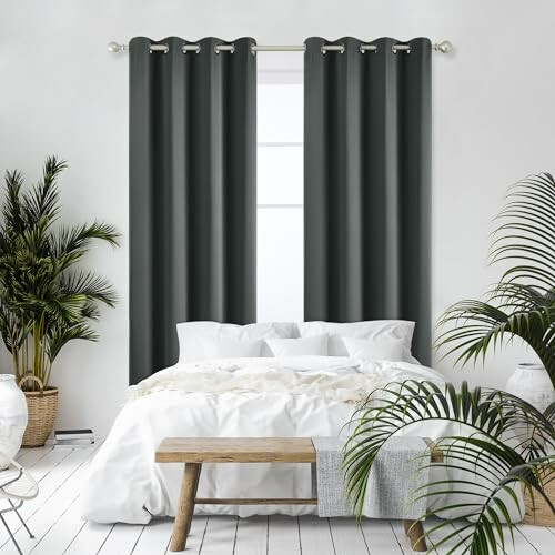 Chambre moderne avec lit blanc et rideaux sombres.