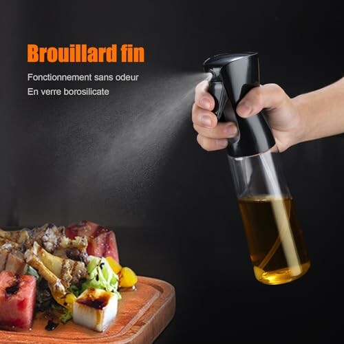 Bouteille de pulvérisation d'huile tenant en main près de nourriture